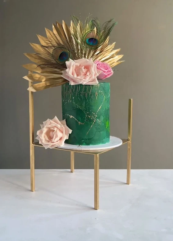Green textured cake decorated with peacock feathers and pink roses